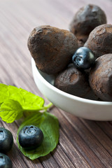 Chocolate truffles with blueberry and mint on wooden background