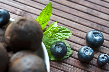 Chocolate truffles with blueberry and mint on wooden background