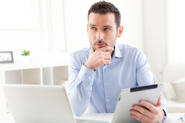 Fototapeta premium Young business man working at home on his tablet