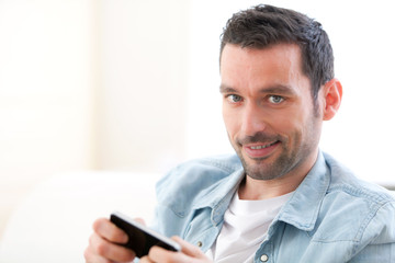Young relaxed man sending text in a sofa