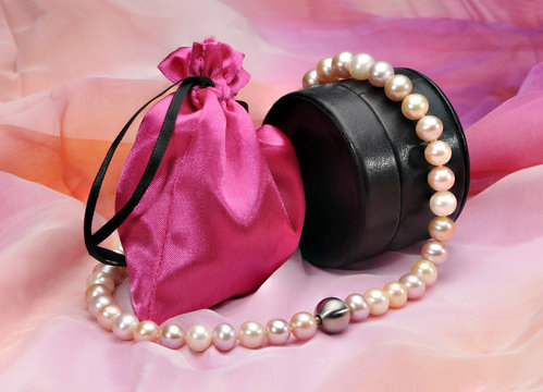 Pearl necklace, black leather case and a pink bag