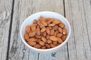 Roasted almonds in a porcelain bowl on a wooden background