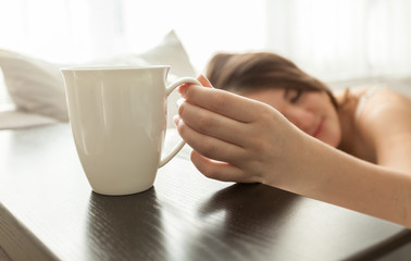 beautiful woman lying in bed and holding cup