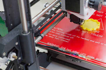 Three dimensional printer creating a yellow object, close up view