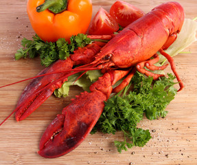 Cooked lobster with various vegetables on wooden board