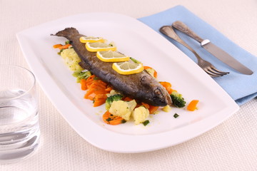 Fried whole trout with vegetables and cutlery