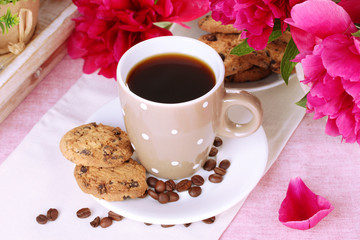 cup of coffee, cookies and flowers on table in cafe