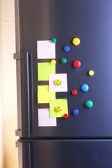 Empty paper sheets and colorful magnets on fridge door