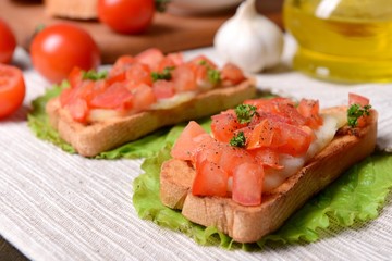 Delicious bruschetta with tomatoes on table close-up