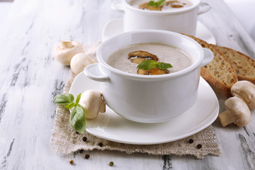 Mushroom soup in white pots, on napkin, on wooden background