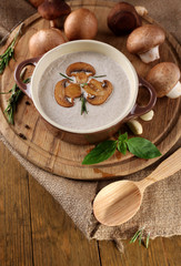 Mushroom soup in pot, on napkin,  on wooden background