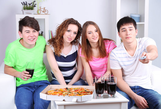 Group of young friends watching television at home