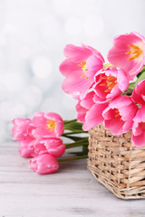 Beautiful pink tulips in basket on wooden table