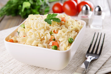 Tasty instant noodles with vegetables in bowl on table close-up