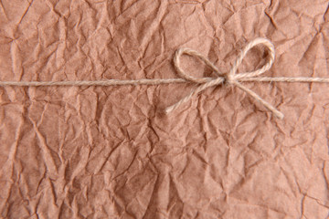 String tied in  bow on brown paper packaging close-up