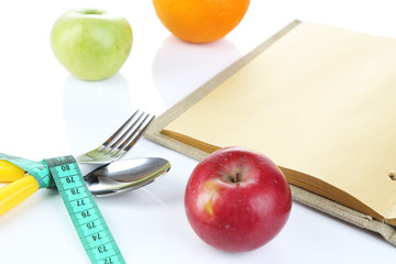 Cutlery tied with measuring tape and book with fruit isolated