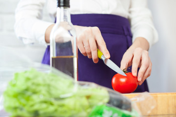 Obraz na płótnie Canvas Female chef cutting a tomato for salad