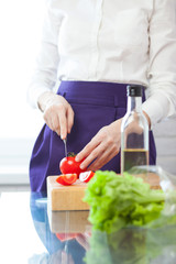 Obraz na płótnie Canvas Vertical shot of female chef cutting tomato