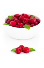 Three red raspberries with fresh mint leaves