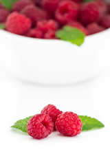 Three red raspberries with fresh mint leaves