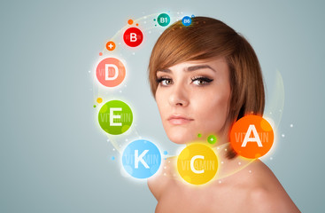 Pretty young girl with colorful vitamin icons and symbols