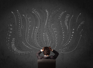 Businessman thinking with sketched arrows in front of a chalkboa