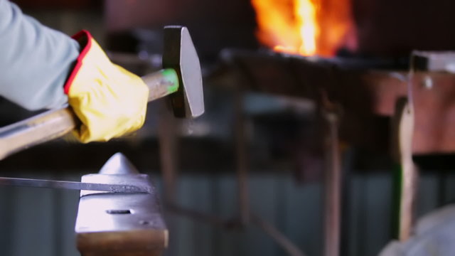 A blacksmith forging hot iron on the anvil.