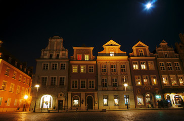 Illuminated facade of the building and moon in Poznan .