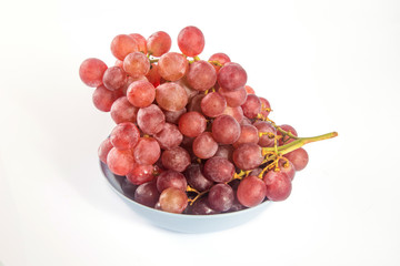 Red grapes in a dish on white background.