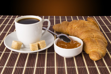Cup of coffee and a croissant and jam