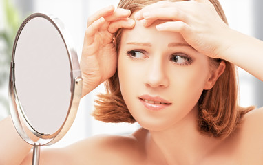 beautiful healthy woman  frightened saw in the mirror acne and w