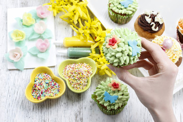 Fototapeta na wymiar Woman decorates easter cupcakes