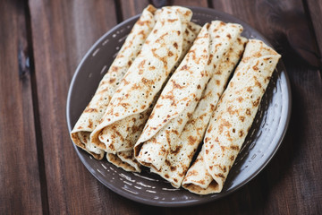 Glass plate with stuffed rolled crepes over wooden background