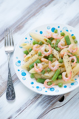 Penne with boiled shrimps and vegetables, vertical shot