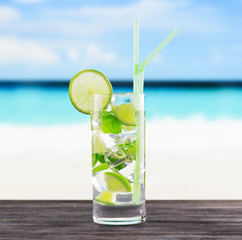 Glass of mojito cocktail on a beach