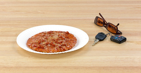 Pizza next to car keys and sunglasses