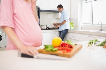 Mid section of woman chopping vegetables with man cooking food