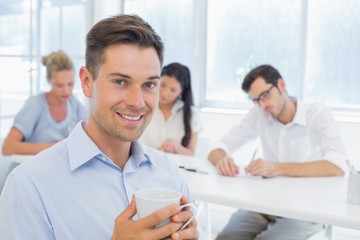 Obraz na płótnie Canvas Casual businessman smiling at camera during meeting