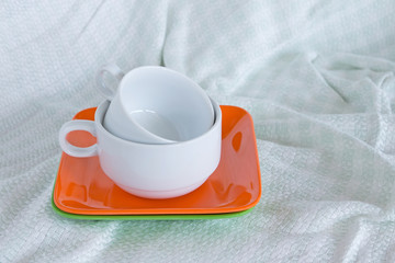 White coffee cups and colorful dish on silk tablecloth