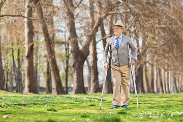 Fototapeta premium Senior gentleman walking with crutches outdoors