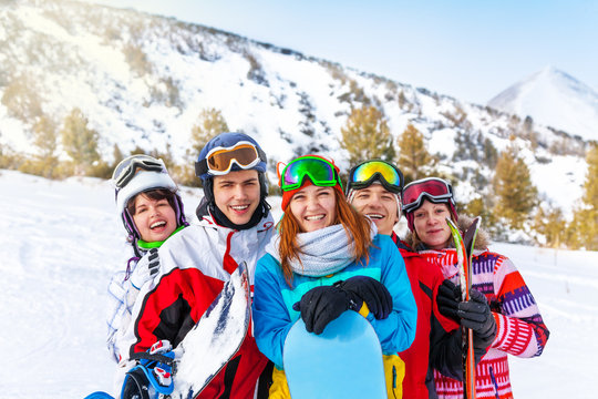 Five smiling friends with snowboards