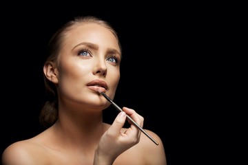 Fototapeta premium Attractive woman applying lip gloss