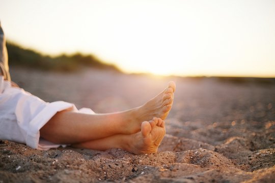 Legs Of Senior Woman Sitting On Beach