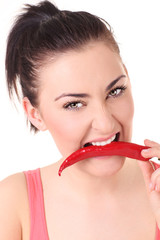 Beautiful woman with chili pepper in mouth. - obrazy, fototapety, plakaty