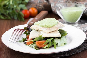 Fried white fish fillet with salad of tomatoes, arugula, herbs