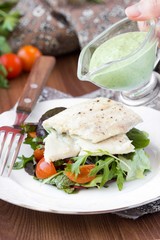 Fried white fish fillet with salad of tomatoes, arugula, herbs