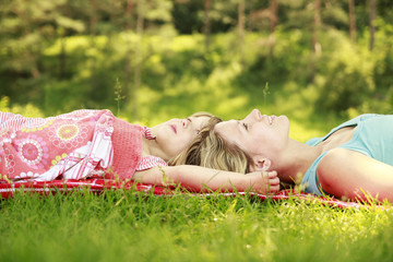 Mama and her little daughter lie on the grass