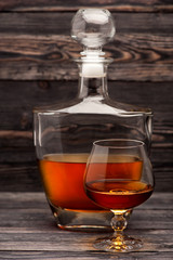 Cognac bottle and glass on wooden background