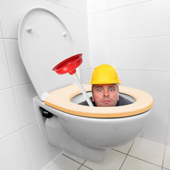 Funny repairman looking from the toilet bowl.