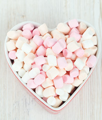 marshmallows in heart shape bowl on a wooden table